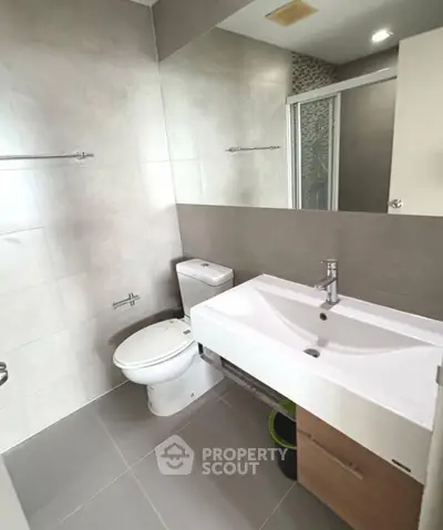 Modern bathroom with sleek fixtures and spacious shower in contemporary apartment.