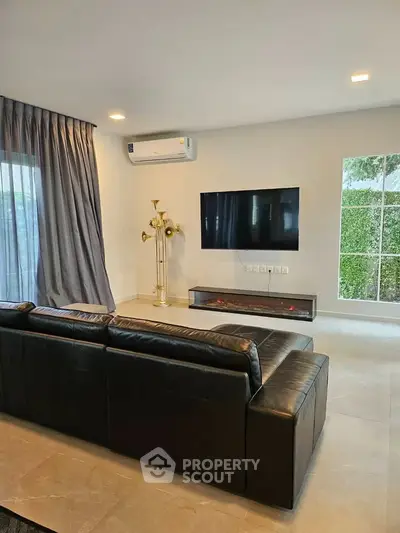 Modern living room with sleek black leather sofa, wall-mounted TV, and elegant floor lamp.