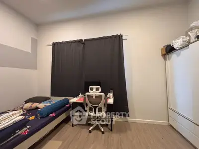 Cozy bedroom with study area, featuring a bed, desk, and chair, ideal for students or professionals.