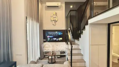 Modern living room with stylish staircase and wall-mounted TV, featuring elegant decor and natural light.