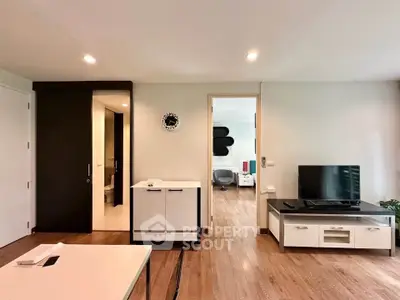 Modern living room with sleek furniture and wooden flooring, featuring a TV unit and stylish decor.