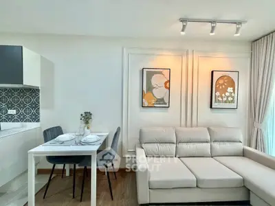Modern living room with stylish decor and open kitchen layout, featuring elegant furniture and wall art.