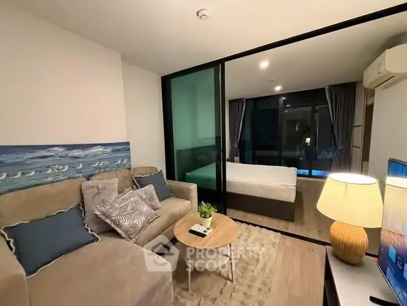 Modern apartment interior with cozy living room and bedroom separated by glass partition.