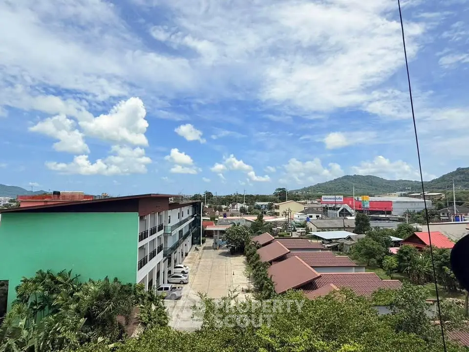 Scenic view of residential and commercial buildings with lush greenery and mountains in the background.