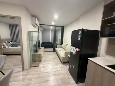 Modern apartment interior with open layout, featuring a cozy living room and sleek kitchen appliances.
