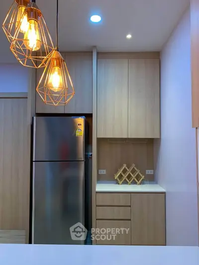 Modern kitchen with sleek wooden cabinets and stylish pendant lighting.