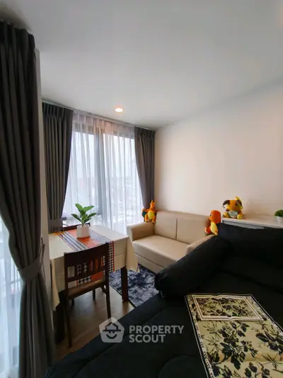 Cozy living room with plush toys and modern decor, featuring large windows and elegant curtains.