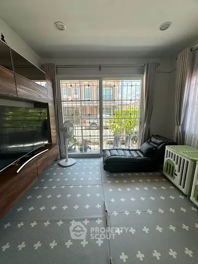 Cozy living room with large window, modern furniture, and soft flooring, perfect for relaxation.