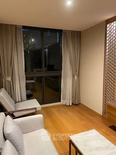 Elegant living room with wooden flooring and large window offering city views, featuring cozy seating and stylish decor.