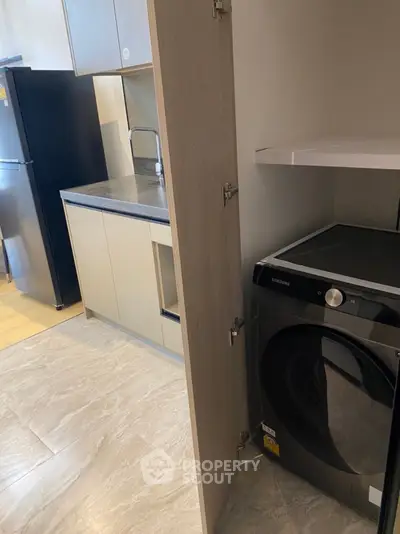 Modern kitchen with sleek appliances and hidden laundry area in stylish apartment.