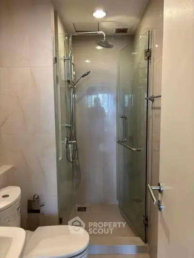 Modern bathroom with glass shower enclosure and sleek fixtures.