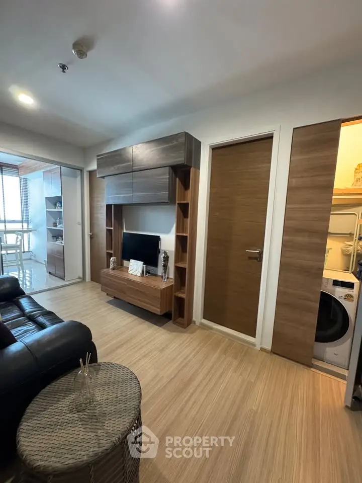 Modern living room with sleek wooden furniture and integrated laundry area, perfect for urban living.