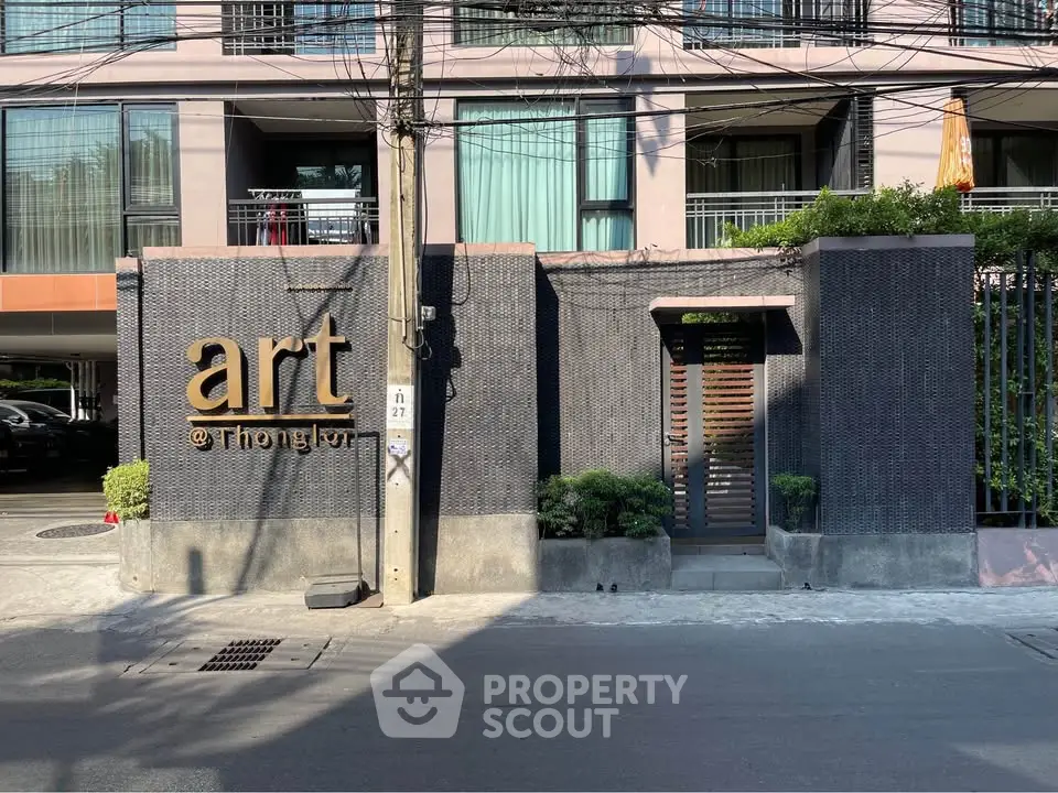 Modern apartment building entrance with stylish facade and greenery at Art @ Thonglor.