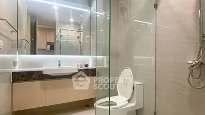 Modern bathroom with glass shower and sleek fixtures in luxury apartment.