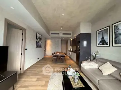 Modern living room with open kitchen, stylish decor, and wooden flooring in a contemporary apartment.