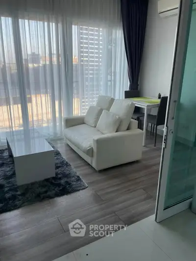 Modern living room with sleek furniture and large windows offering city views.