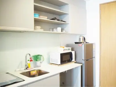Modern kitchen with sleek cabinetry, stainless steel fridge, and microwave in a compact layout.