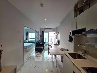 Modern open-plan apartment with sleek kitchen and spacious living area leading to a balcony with a view.