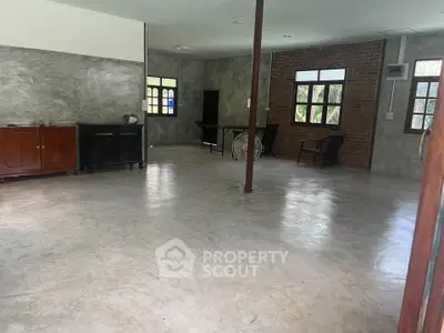 Spacious industrial-style living room with polished concrete floors and rustic brick accents.