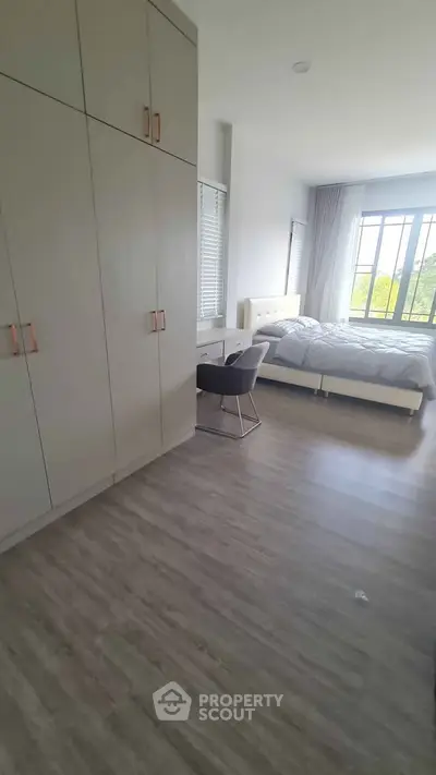 Spacious bedroom with large windows and modern furnishings