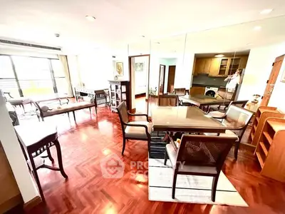 Spacious living room with elegant wooden flooring and classic furniture in a bright apartment.