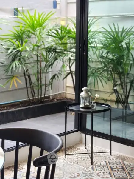 Chic patio corner with modern decor and lush greenery view.