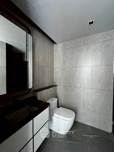 Modern bathroom with sleek design and elegant fixtures, featuring a stylish mirror and contemporary toilet.