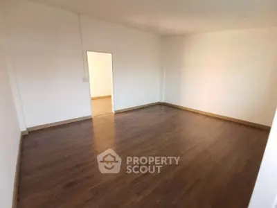 Spacious empty room with wooden flooring and white walls, ideal for customization.