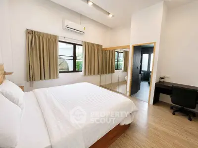 Spacious bedroom with modern decor and ensuite bathroom, featuring large windows and a study area.