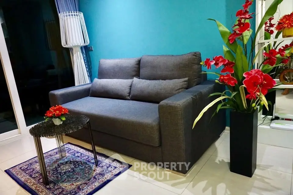 Stylish living room with modern gray sofa and vibrant red flowers