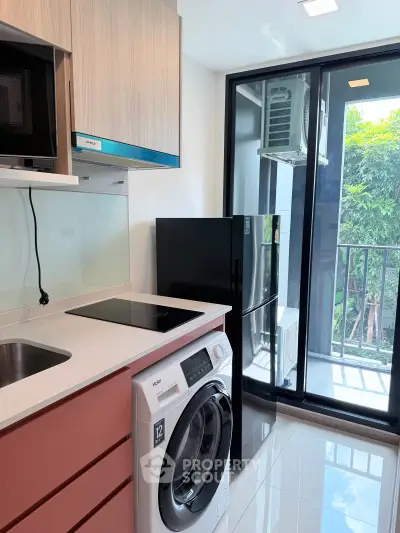 Modern kitchen with sleek appliances and balcony view in a stylish apartment.
