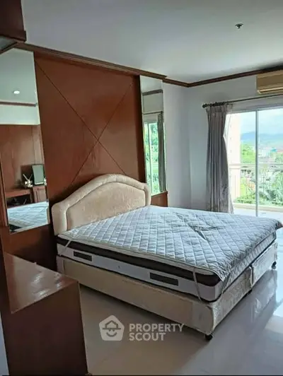 Spacious bedroom with large windows and balcony access, offering natural light and scenic views.