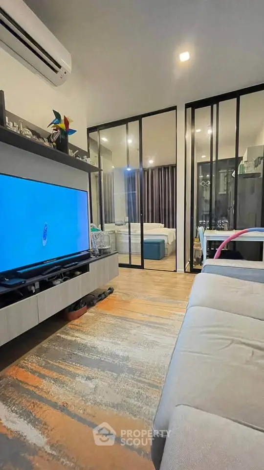 Modern living room with sleek design and glass partition leading to bedroom