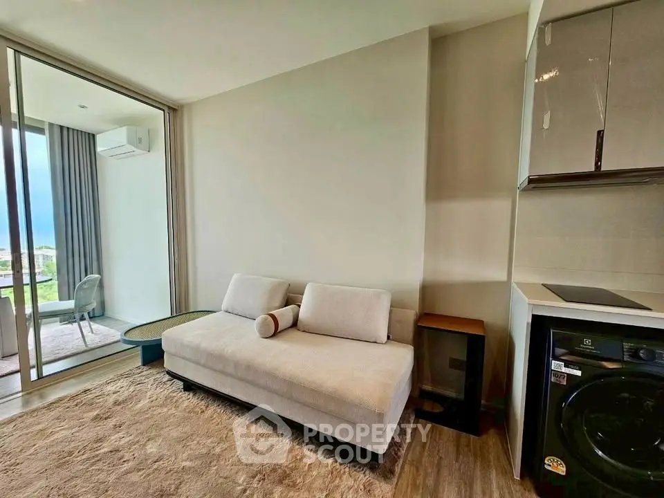 Modern living room with cozy sofa and washing machine, featuring a balcony view.