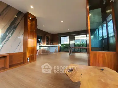 Spacious modern living room with wooden accents and large windows offering natural light.