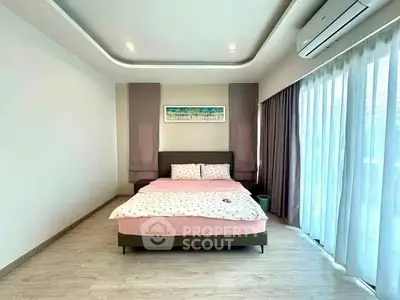 Spacious bedroom with modern decor and large windows for natural light.