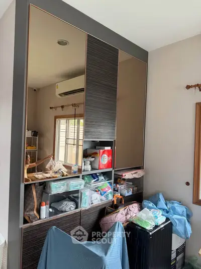 Modern bedroom with built-in storage and large mirror reflecting natural light.