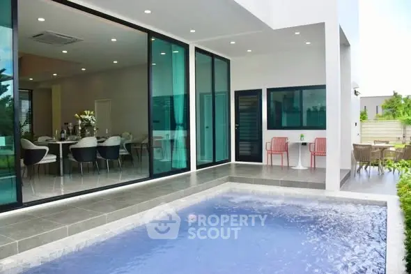 Luxurious modern home with pool and spacious outdoor seating area.