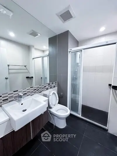 Modern bathroom with sleek design, featuring a glass shower enclosure and stylish sink.