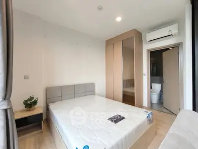 Modern bedroom with mirrored wardrobe and ensuite bathroom in stylish apartment.