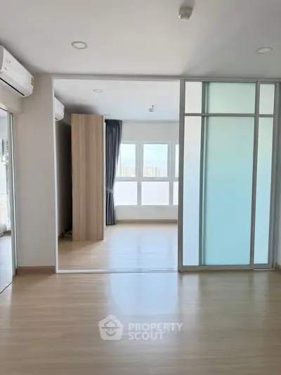 Spacious modern apartment with sliding glass doors and large windows offering city views.