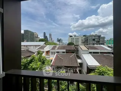 Stunning cityscape view from a balcony overlooking urban skyline and lush greenery.