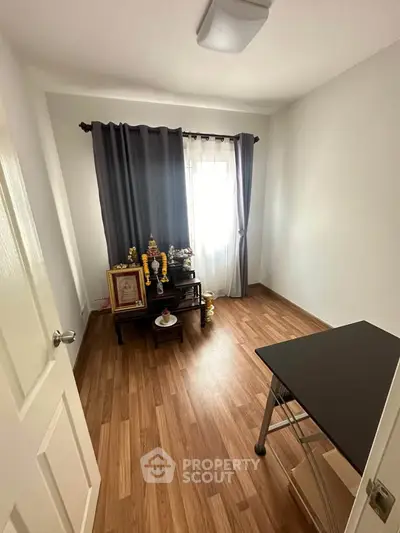 Cozy study room with wooden flooring and natural light, perfect for focused work or relaxation.