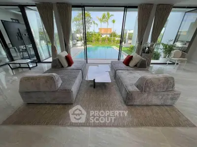 Luxurious living room with modern sofas and pool view, perfect for relaxation and entertainment.