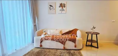 Stylish living room with cozy sofa, elegant decor, and natural light through sheer curtains.