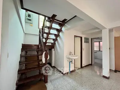 Spacious interior with wooden staircase and tiled flooring in a bright home