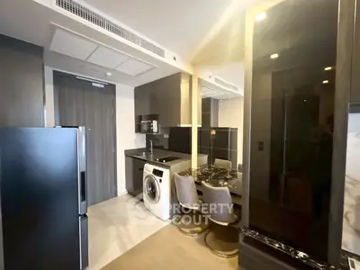 Modern kitchen with sleek appliances and compact dining area in stylish apartment.