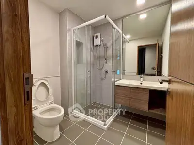 Modern bathroom with glass shower enclosure and sleek vanity in contemporary apartment.