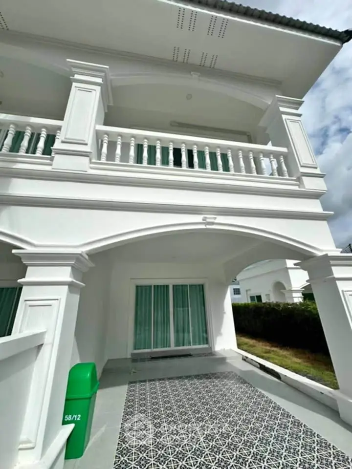 Elegant white two-story house with balcony and patterned driveway