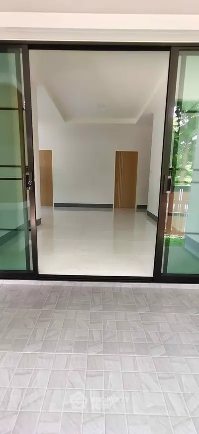 Spacious modern interior with sliding glass doors and tiled flooring, perfect for natural light and open living.